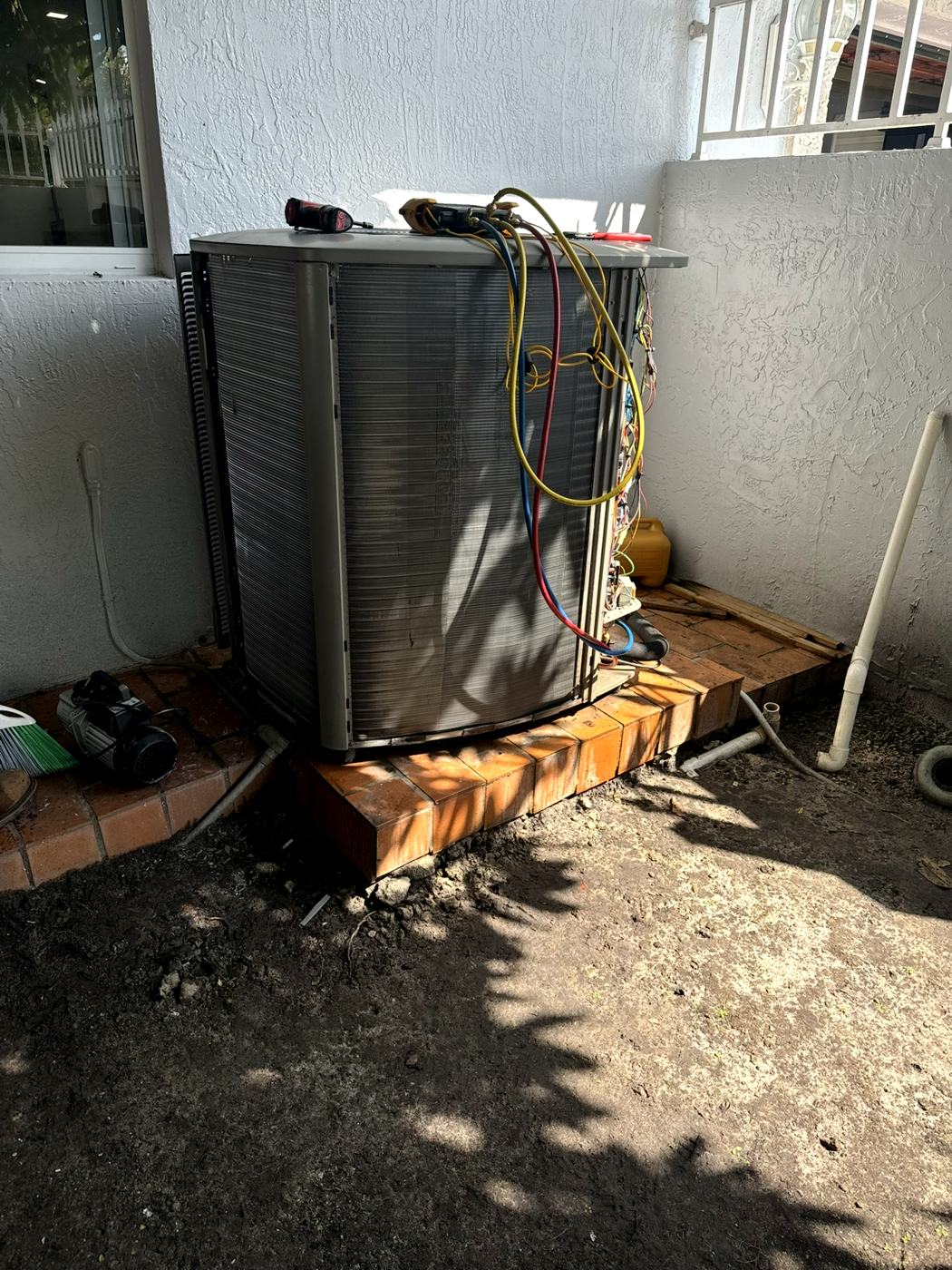 Condensadora de aire acondicionado en el patio de una casa, con manómetros